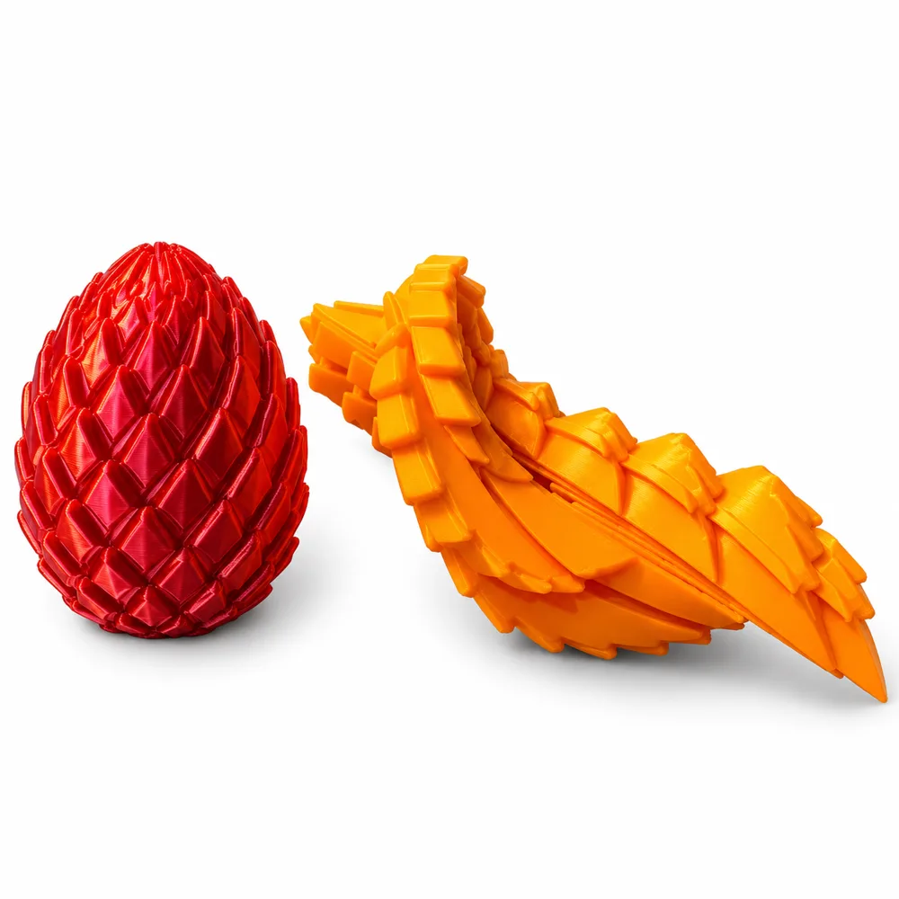 A red 3D printed dragon egg next to an orange articulated dragon