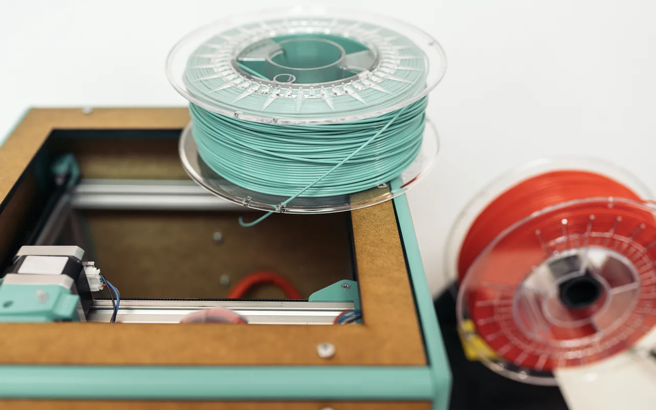 Teal and red filament spools beside a 3D printer