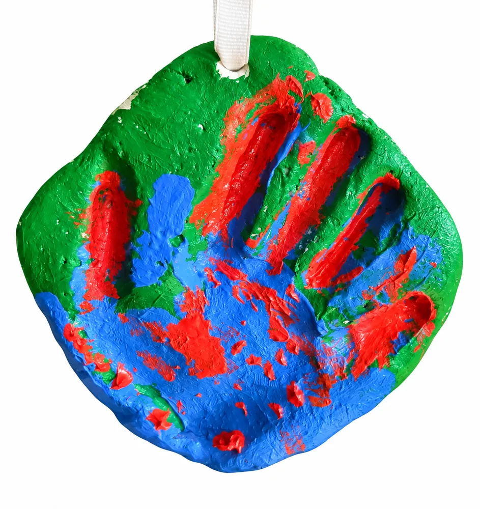 A child's painted handprint keepsake in green, blue and red, hanging from a white ribbon